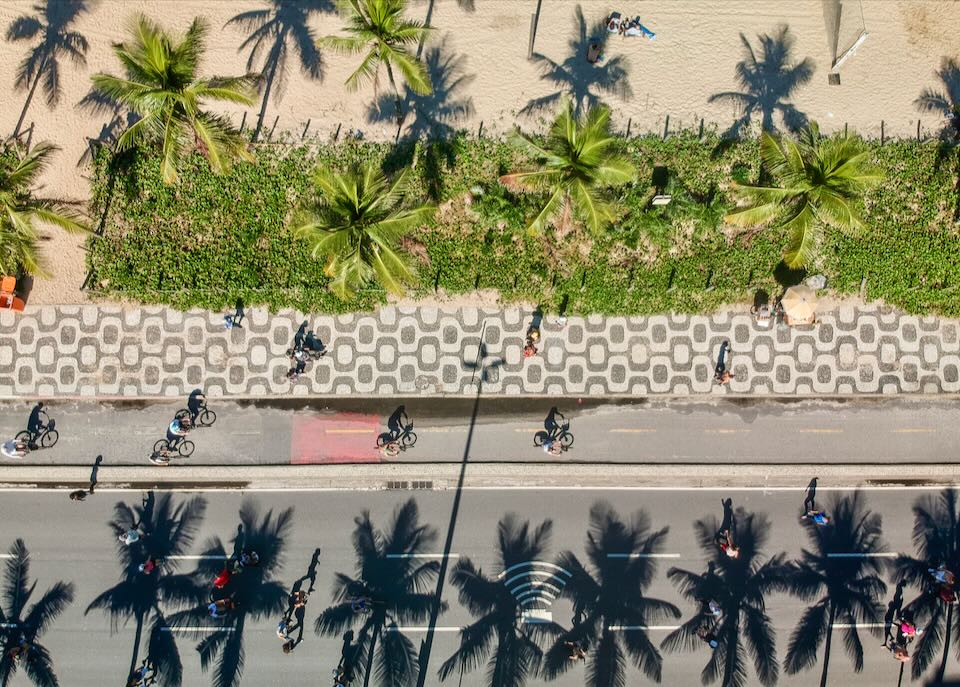 Overhead view of bicyclists and palm trees along the famous patterned promenade at Ipanema Beach. 