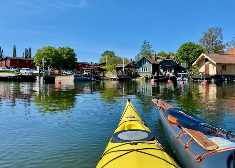 View over kayak tips to small houses perched over a picturesque harbor