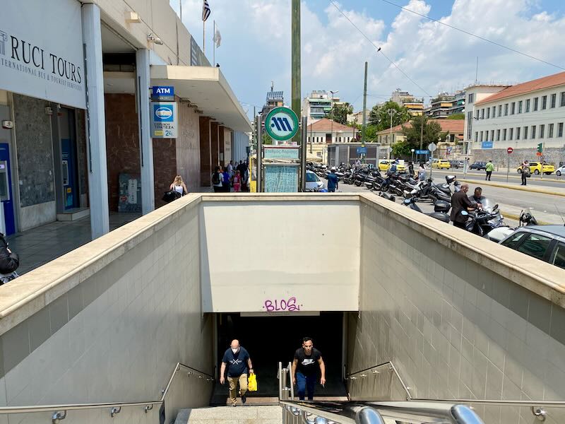 Entrance to an underground metro station, with people coming up the escalators