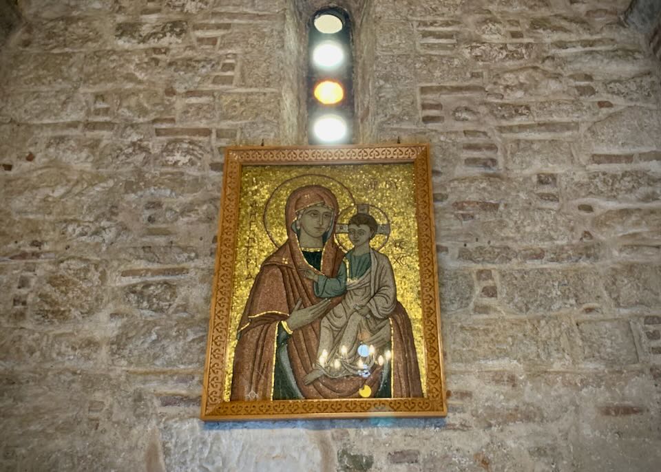 A Greek Orthodox mosaic of the madonna and child next to a small stained glass window