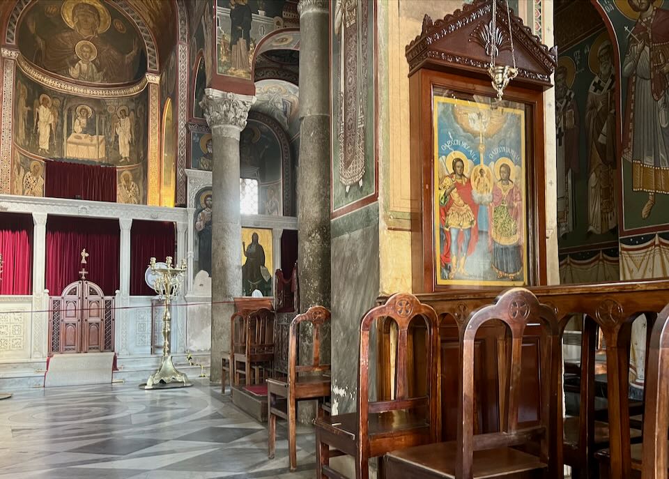 Center aisle and wooden chairs in a Greek Orthodox church.