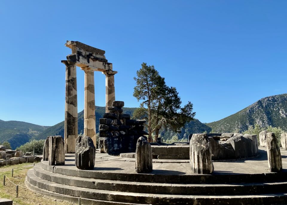 Ruins of a circular tholos temple with a mountain backdrop