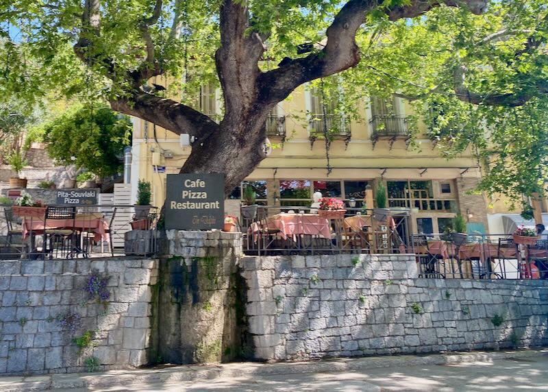 Greek Taverna with rustic tables set under a large plane tree.