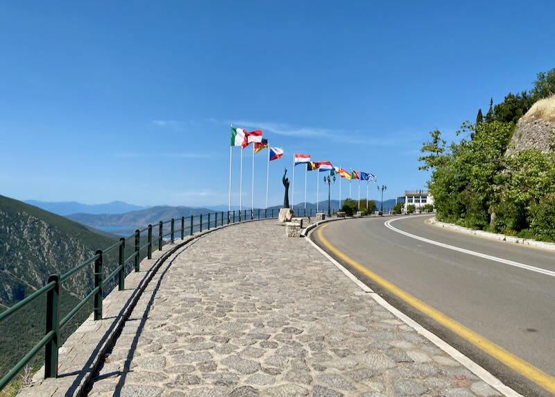 Curved, paved road in the mountains, lined with national flags.