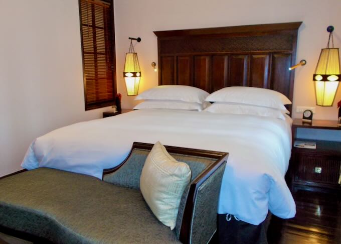 A dark wood bed frame with white pillows and comforter.