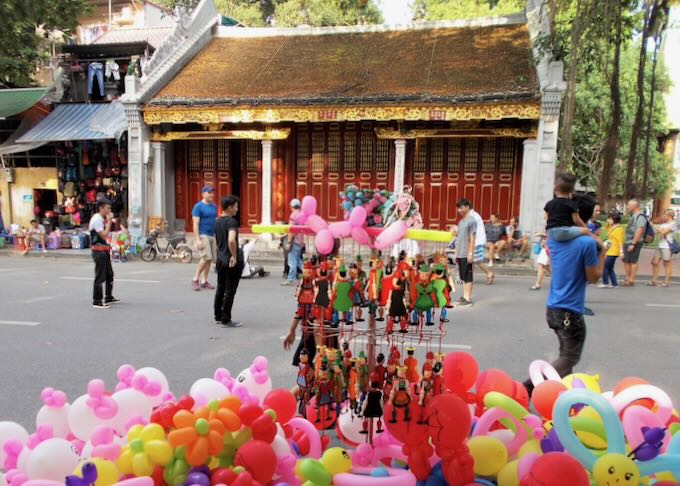 Colorful balloons sit on a sidewalk in front of a temple.