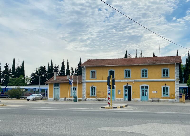 Small, yellow train station in a Greek village.