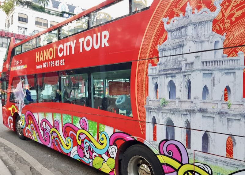 A red bus with Hanoi City Tour printed in white on its side.