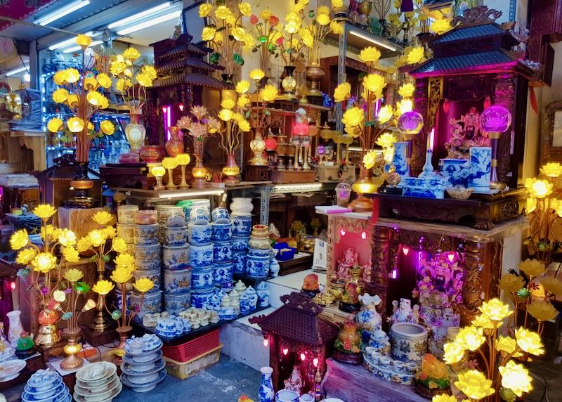 Bright lit yellow flowers sit with cobalt blue painted ceramics for sale in a shop.