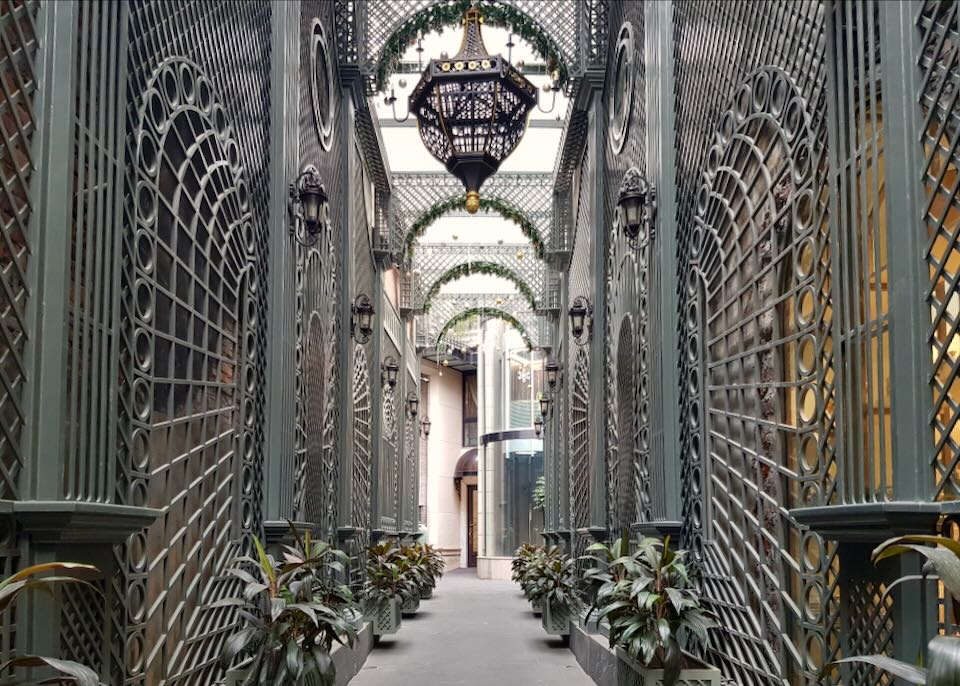 A green gray painted ornate metal fence lines a path to the hotel entrance.