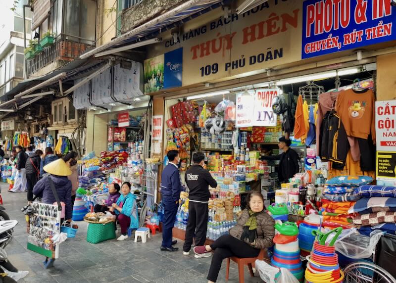 Women sit outside shops in Vietnam to sell products.