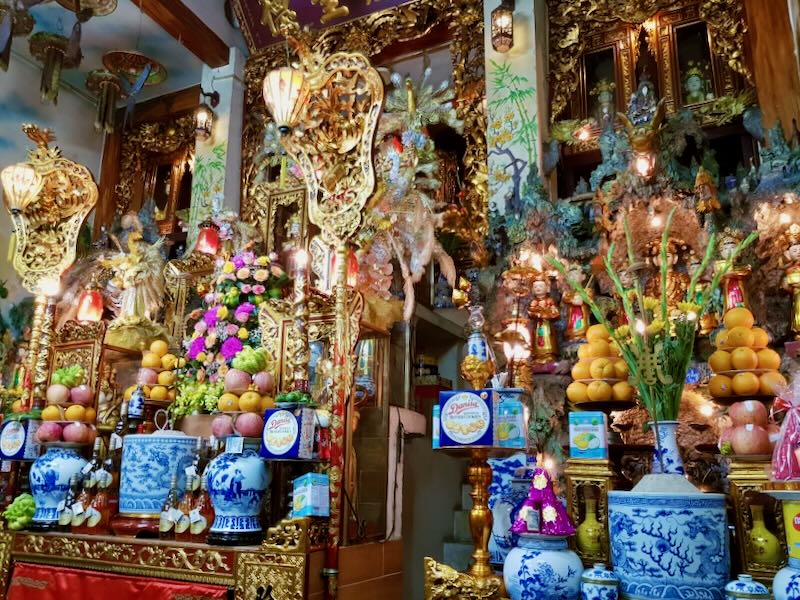 Gold pedestals and shelves hold lemons, oranges, plants, and figurines at a temple in the old quarter in Hanoi Viet Nam.