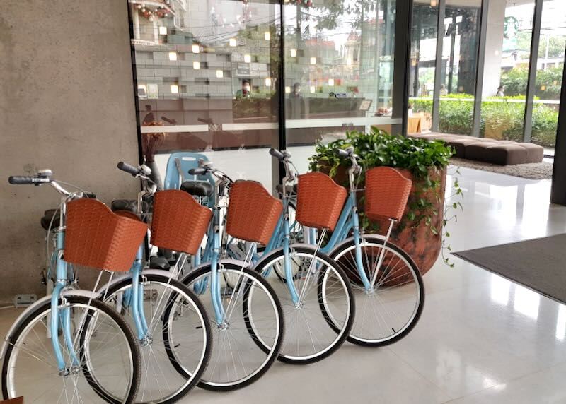 A row of pale blue bicycles sit inside the lobby of a hotel.