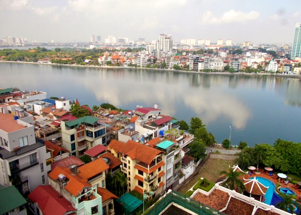 From a tall building, the view of a lake and rooftops in Hanoi, Vietnam.