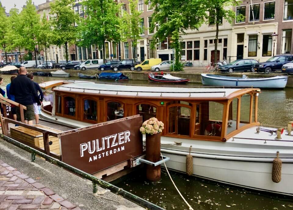 A polished wooden-sided boat on a canal in Amsterdam.