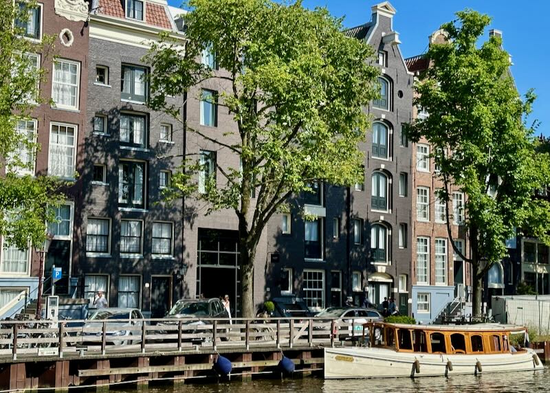 Amsterdam townhouse hotel on a canal with boat in front