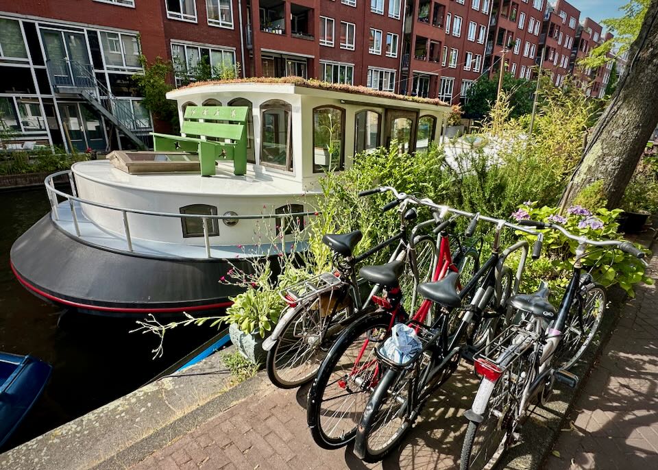 Bikes parked next to a houseboat on an Amsterdam canal