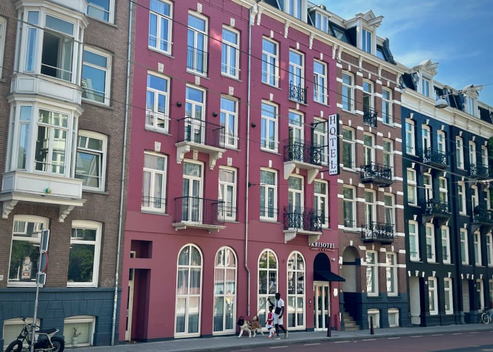 Rose colored townhouse-style hotel, with a family walking past