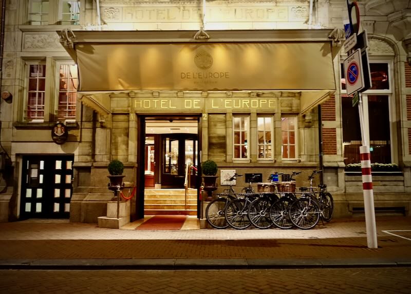 Entrance of a luxury hotel at night, with a row of bicycles parked in front.