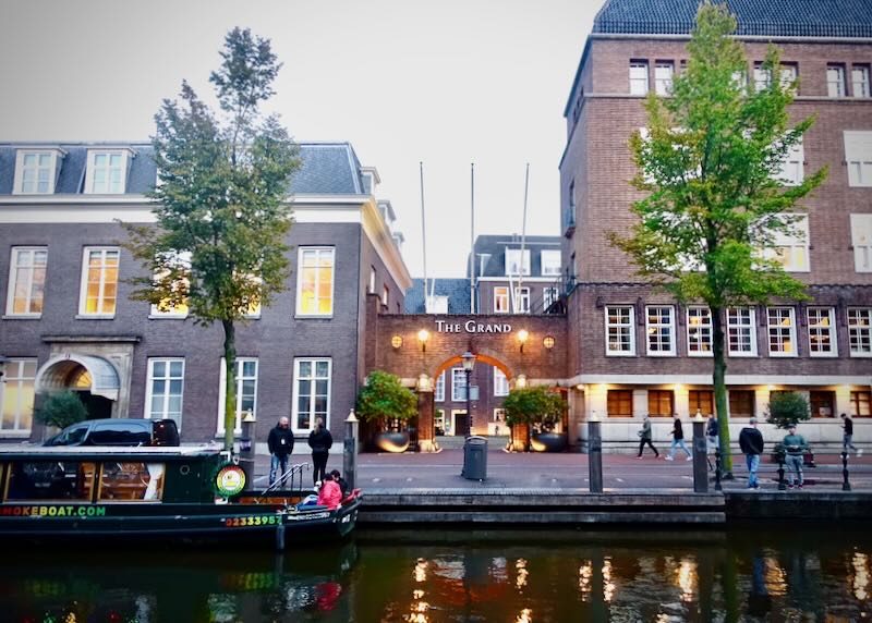 View across an Amsterdam canal of a swanky luxury hotel.