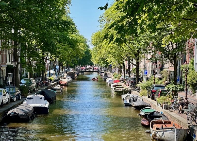 Narrow tree-lined canal with boats parked along both sides