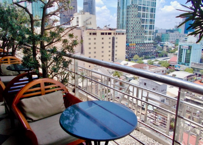 A balcony with tables overlooks a city.