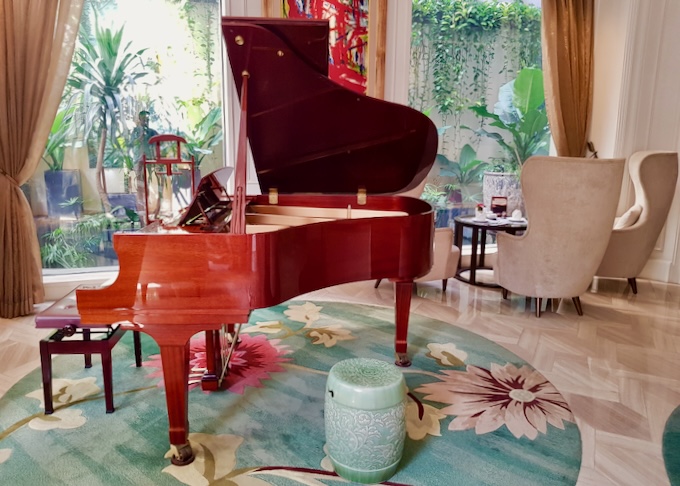 A cherry wood grand piano sits in a lobby.