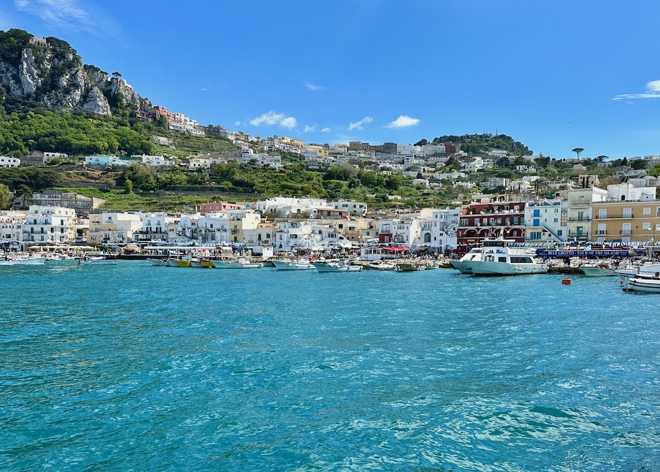 View of Marina Grande, the main port of Capri Island, as seen from the sea with pleasure boats, colorful buildings, and mountains
