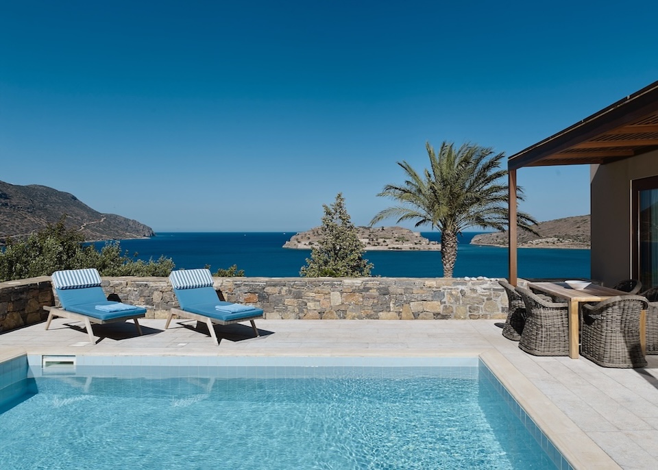 Sea-facing pool with sunbeds and Spinalonga Island in the background at Blue Palace resort in Crete