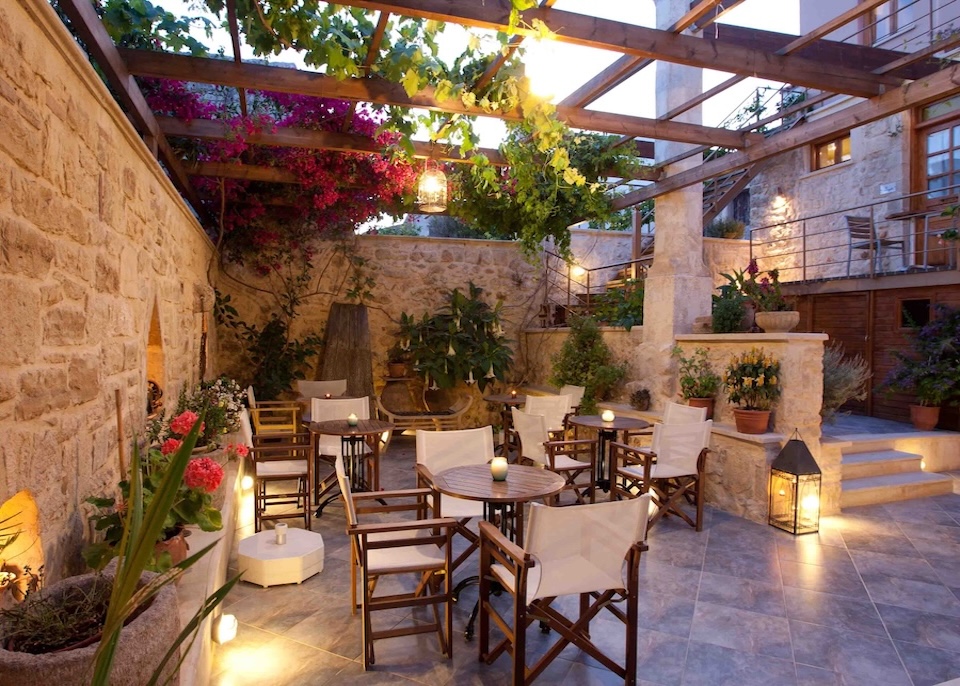 Almost sunset under the pergola in a stone courtyard dining area with bougainvillea and vines at Casa Vitae hotel in Crete