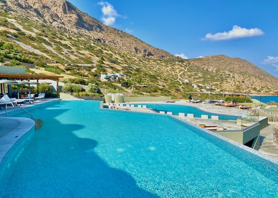 Two pools terraced on the hillside and separated by sun decks facing the sea at Cayo Exclusive Resort in Crete