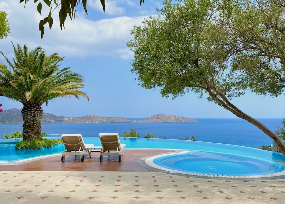 Curved infinity pool with round jacuzzi attached at one end overlooking the sea at Elounda Gulf resort in Crete