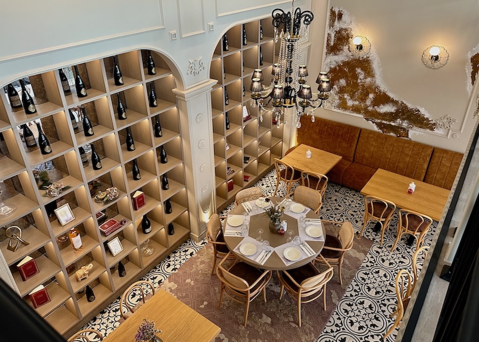View from above a restaurant with decorative tile floor, shelves with wine and books, and wooden tables at Legacy Gastro Suites in Crete