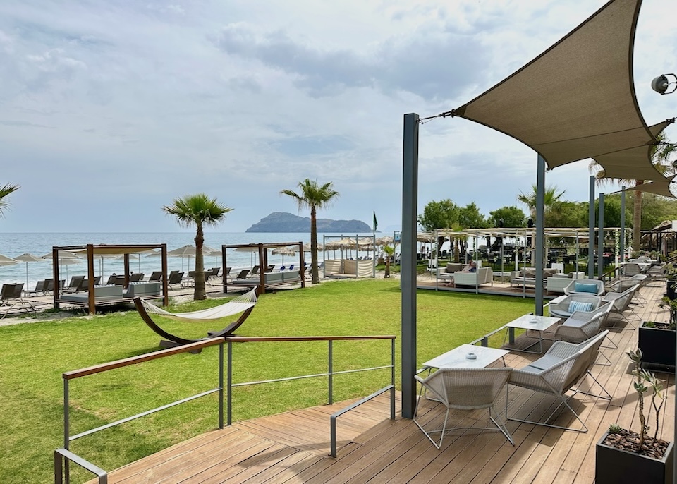 Sunbeds and Bali beds on the beach with a sea view dining terrace at Minoa Palace in Crete
