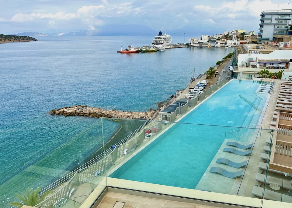 View over the infinity pool and sea toward the port at Niko Seaside Resort in Crete