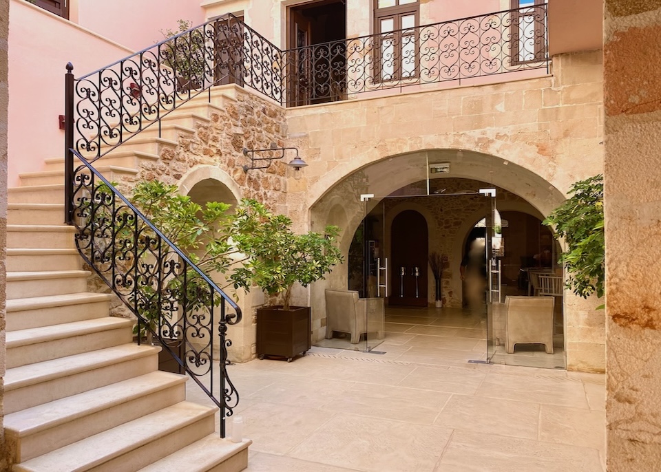 Marble staircase with a wrought iron balcony leading up from the stone-built courtyard at Serenissima hotel in Crete
