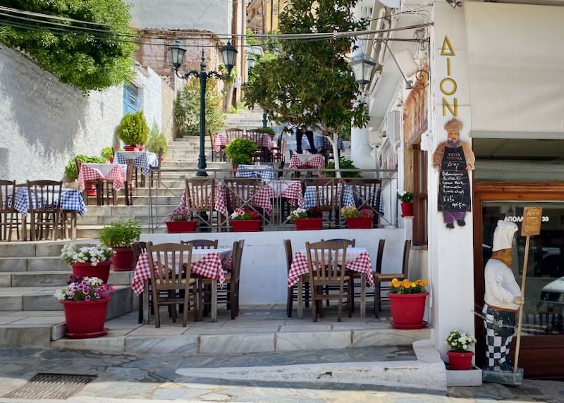 Greek taverna with tables arranged on steps leading up a hillside.