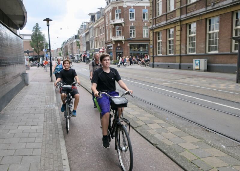 Two young boys riding bikes through the streets of Amsterdam
