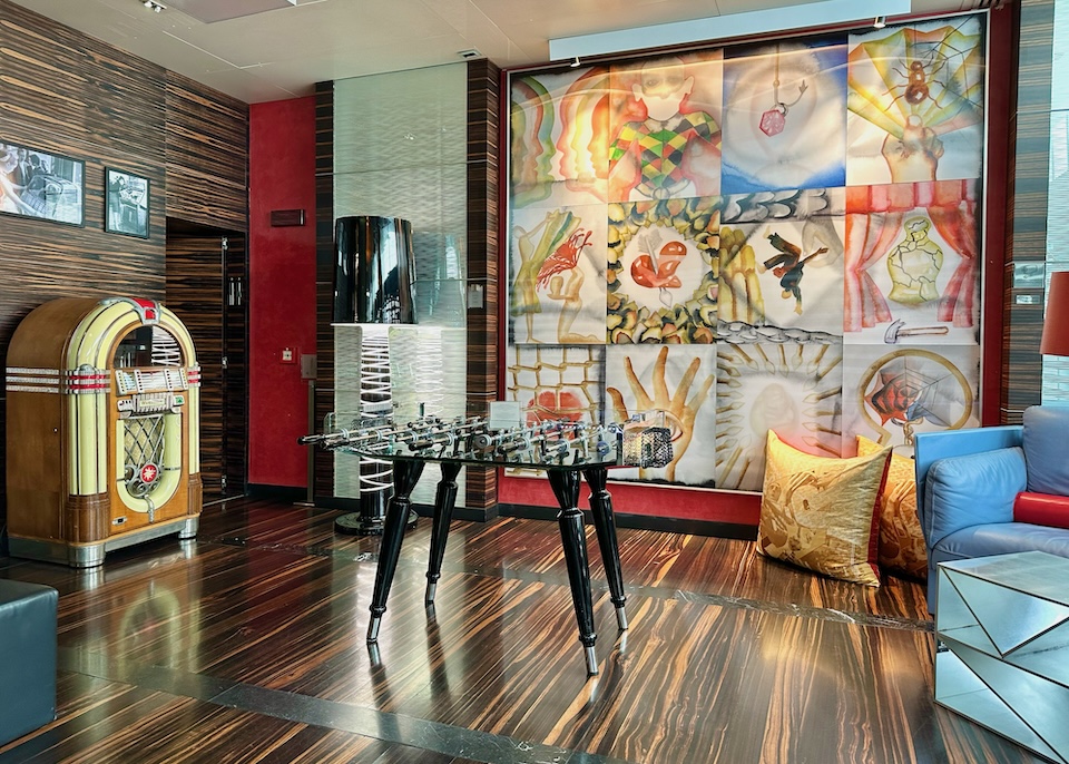 Vibrant wall art, a foosball table, and jukebox in the game room of Romeo Hotel in Naples