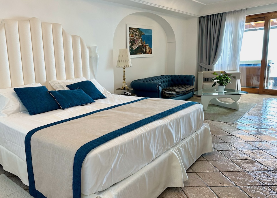 King-sized bed and tufted sofa in a Suite with Jacuzzi at Eden Roc hotel in Positano
