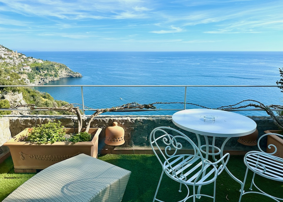 A grassy terrace and al fresco dining table for two with a sea view at Il Piccolo Santandrea hotel in Praiano