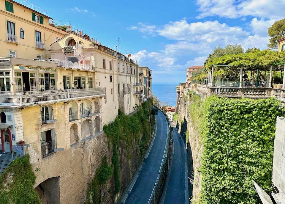 Curved road toward the sea set far below the clifftop buildings dovered in vines in central Sorrento