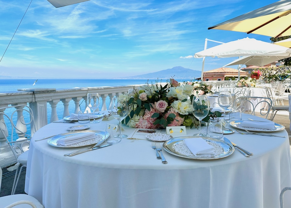 Floral centerpiece on a table in front of a white balustrade on a sea-facing terrace at Hotel Cocumella in Sorrento