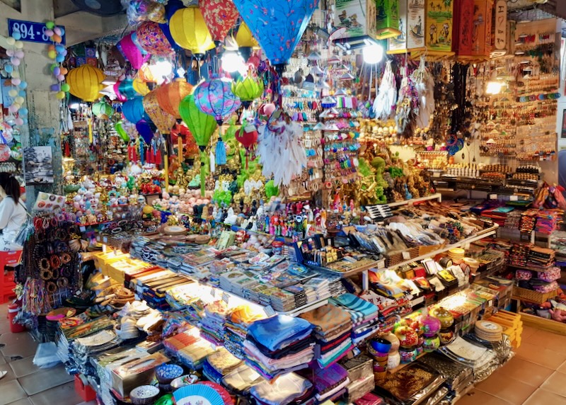 A packed market store with shirts, lanterns, and trinkets.