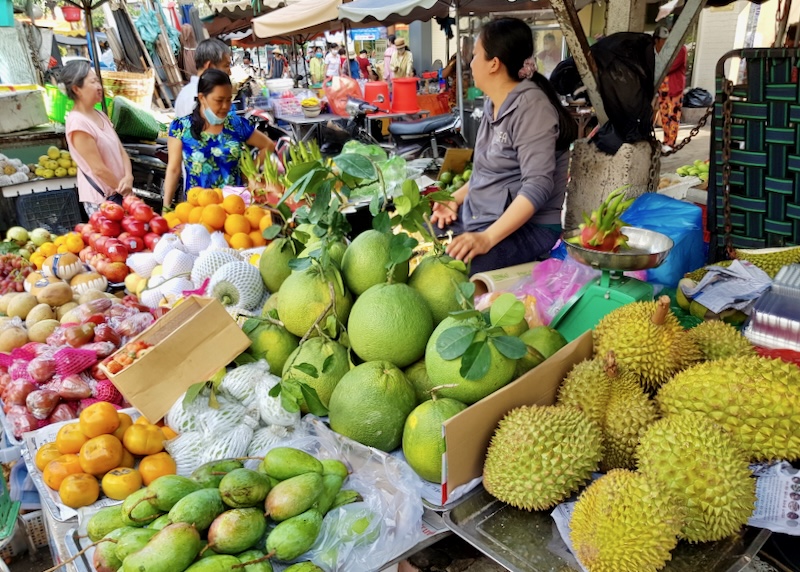 Women buy colorful fruits from a stand.