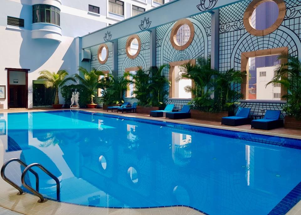 A royal blue pool sits in the shade from elaborately painted walls that look like metal arches.