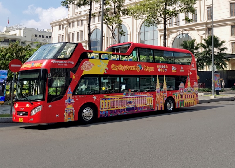 A large double decker red bus waits on the side of the street.