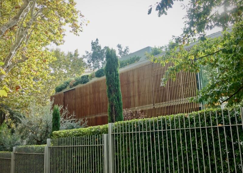 Modern slatted-wood building behind a garden hedge