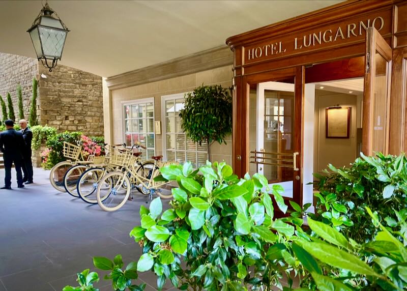 Exterior entrance of a hotel with bicycles to rent and doormen at the ready