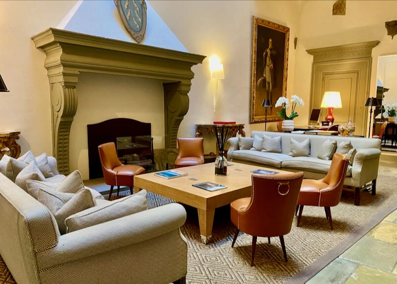 Comfortable looking hotel lounge with leather sofas around a large fireplace.